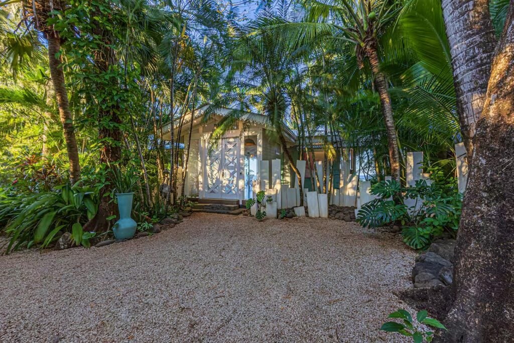 Almost hidden by vibrant tropical plants, the secluded entrance to the house disguises the whole story beyond.