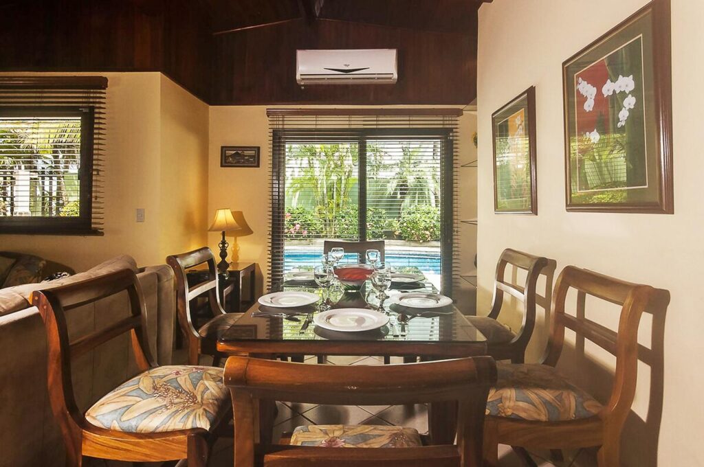 A large dining table for six sits by sliding doors with a view of the inviting pool.