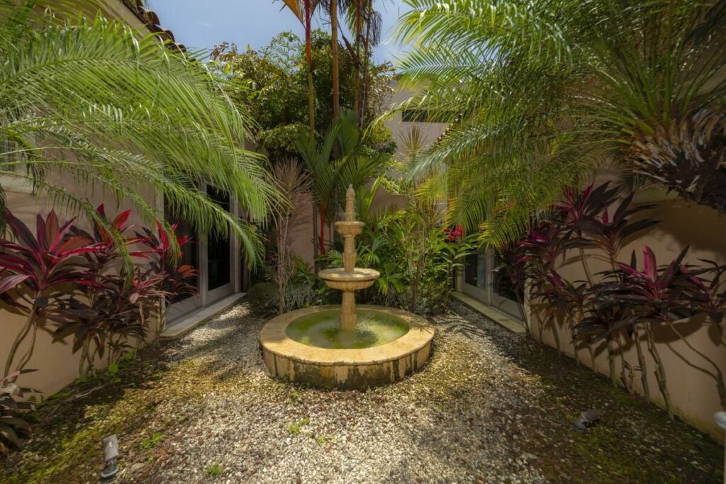 A private tropical courtyard with a central fountain creates a peaceful, garden-like retreat within the home.