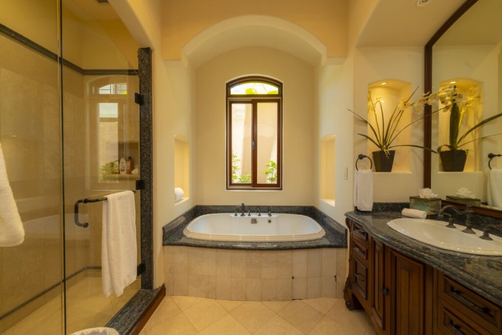 A refined bathroom with a soaking tub beneath a window and a glass-enclosed walk-in shower.
