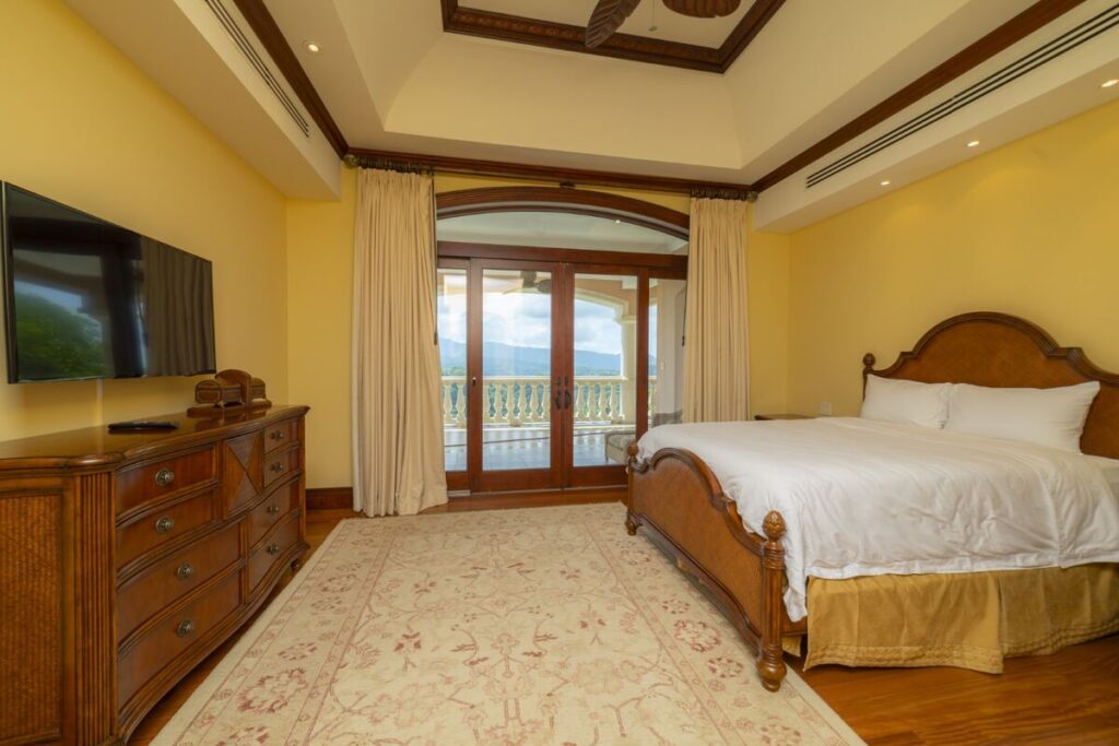 A spacious bedroom with ocean-view balcony access and warm hardwood finishes.