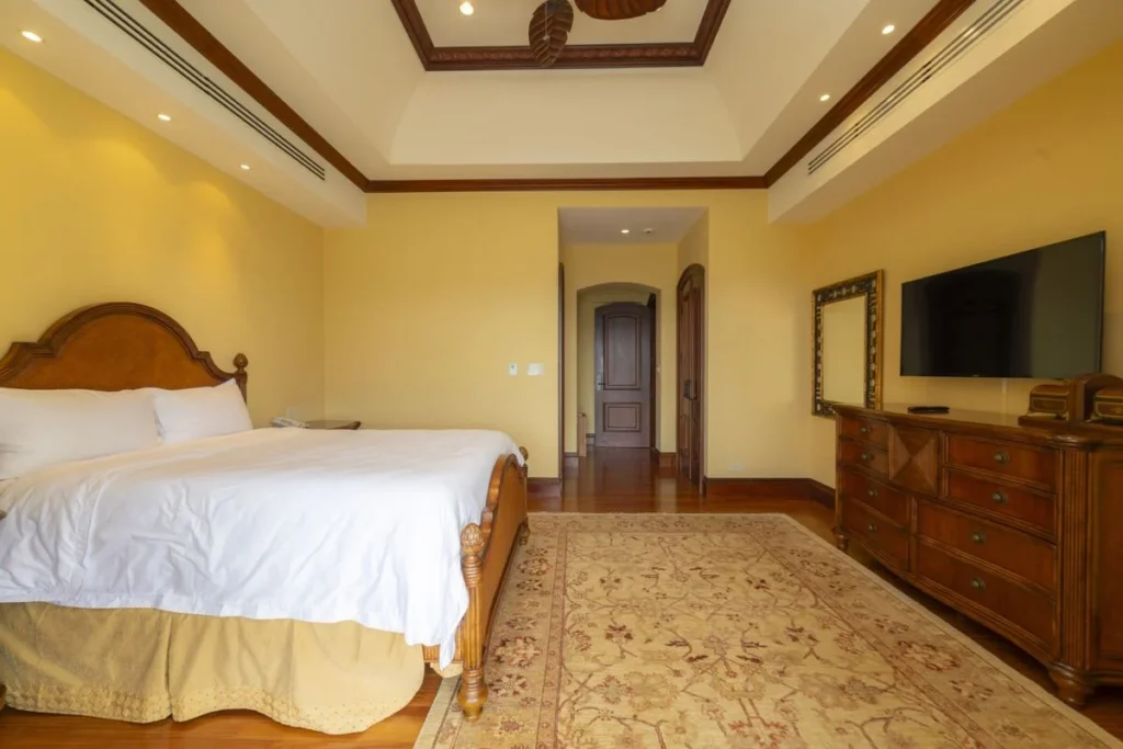 A spacious bedroom with warm hardwood floors, classic furnishings, and a comfortable layout.