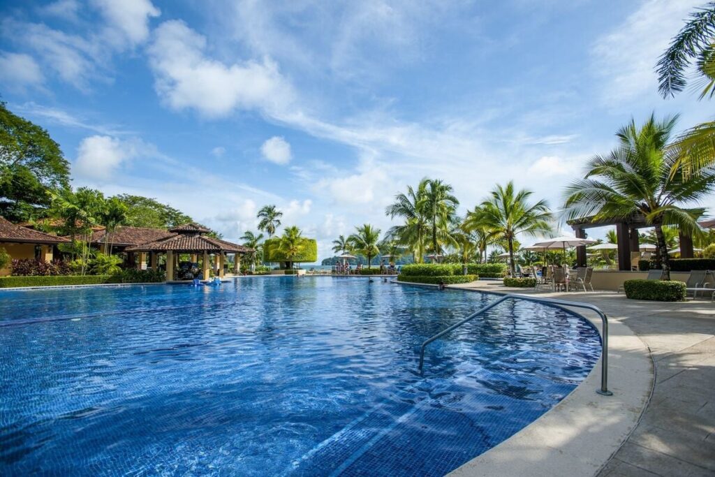 A resort-style pool framed by palms, just steps from the ocean at Los Sueños.
