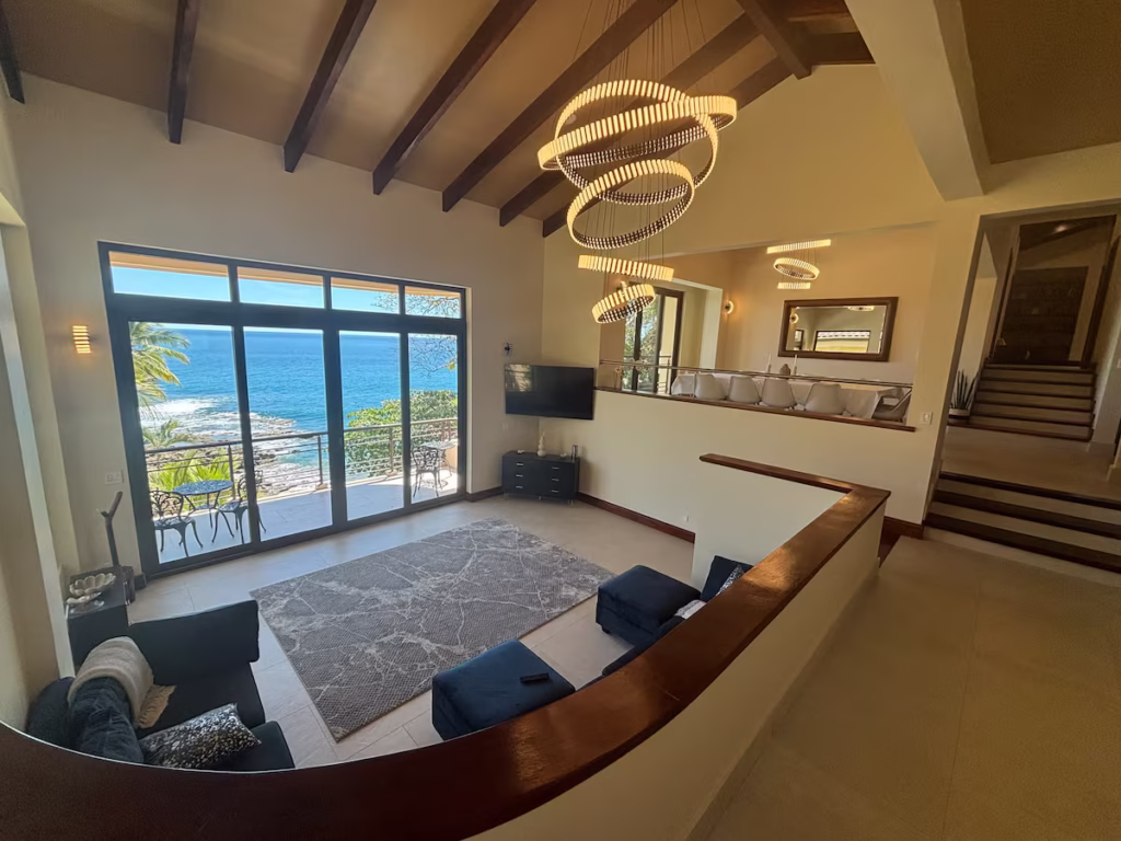 Floor-to-ceiling glass doors frame beautiful Pacific Ocean views while connecting the living room to the outdoor terraces.
