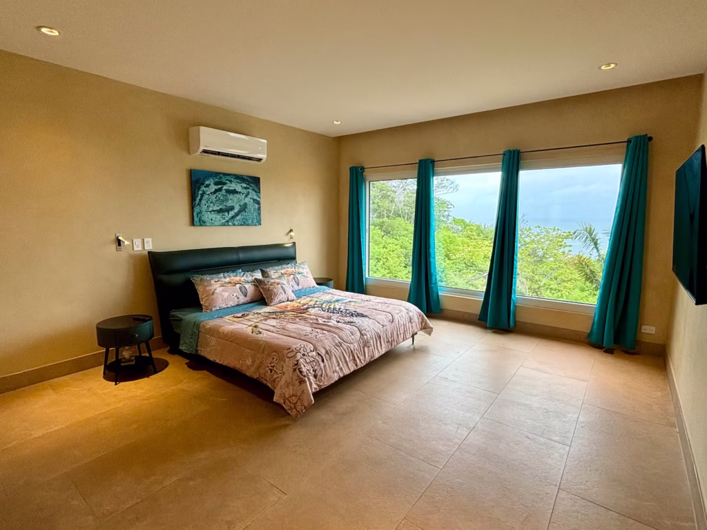 A spacious king bedroom offers peaceful views of the tropical forest and glimpses of the Pacific Ocean.