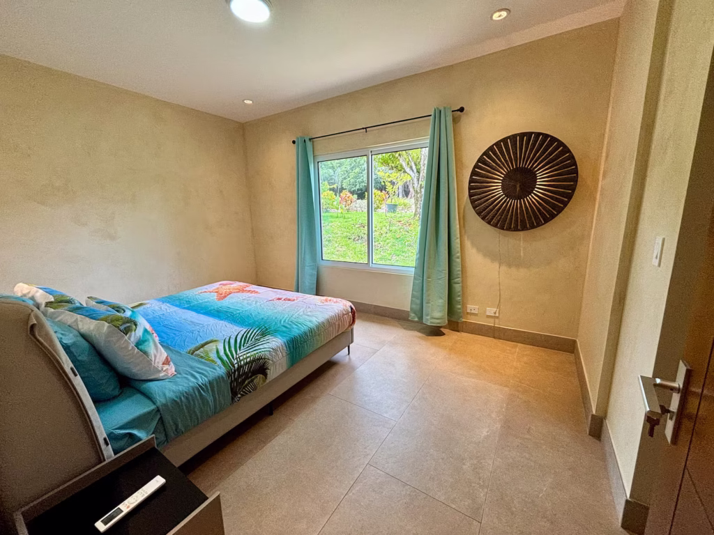 Large windows fill this peaceful bedroom with natural light and views of the surrounding tropical gardens.