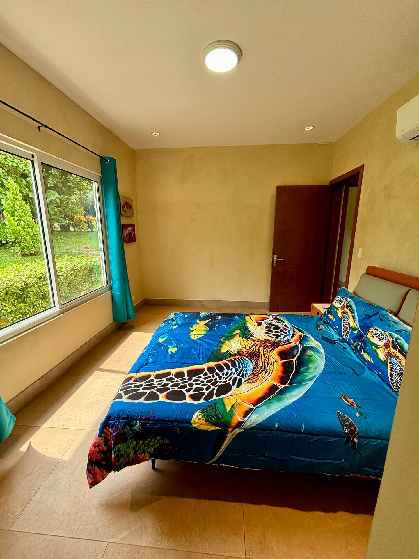 Guest bedroom with sea turtle bedding, garden view, and air conditioning in a Costa Rica vacation villa