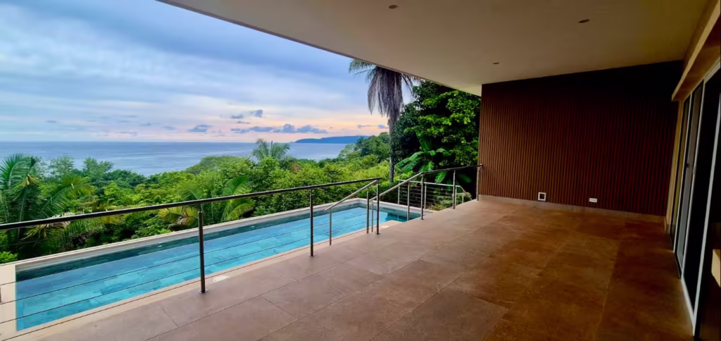 The covered terrace overlooks the pool and Pacific coastline, creating a peaceful setting for outdoor meals and sunset views.